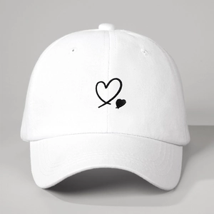Close-up of heart embroidery on a white cotton baseball cap with fine stitching detail
