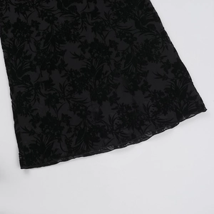 Close-up of black floral jacquard fabric showing semi-transparent texture and flocking detail