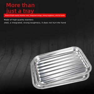 Detail of square stainless steel grill pans with striped bottom on wooden background