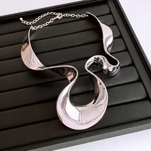 Exaggerated silver wavy metal necklace with a high-shine finish and sleek fluid design