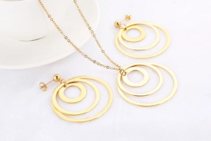 Detail view of gold triple-ring interlocking necklace and earrings set on white background