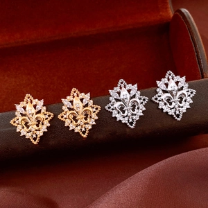 Macro detail of 18k gold and silver fleur-de-lis earrings with shimmering white zircons