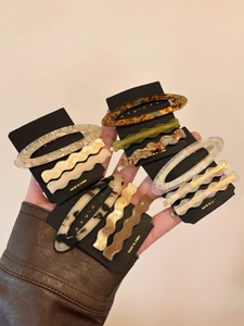 Macro detail of assorted acetate hair clips with shell patterns on black card
