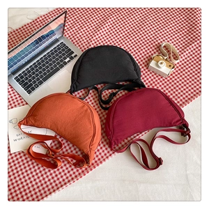 Three colorful nylon crescent crossbody bags in black, orange, and burgundy colors