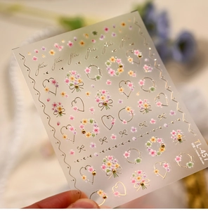 Macro detail of French floral nail art stickers with embossed petals and gold accents