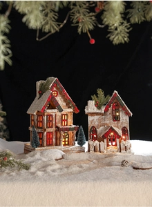 Macro detail of LED glowing wooden Christmas cabin with snow texture and pine needles