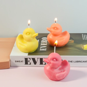 Three colorful 3D little duck scented candles in yellow orange and pink for home decor