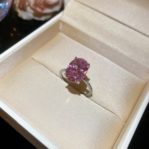 Macro shot of an oval pink gemstone ring in a gift box with pavé diamond band details