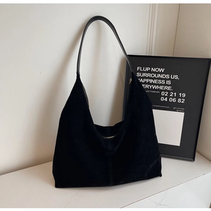 Detail of minimalist black faux suede hobo bag with zipper on marble surface