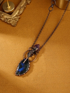 Détail du pendentif crâne de corbeau en bronze avec pierre labradorite et améthyste