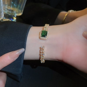 Macro shot of gold cuff bracelet featuring emerald zircon and white sparkling stones