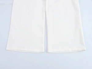 Dettaglio ravvicinato dell'orlo dei pantaloni bianchi con trama del tessuto e cuciture fini