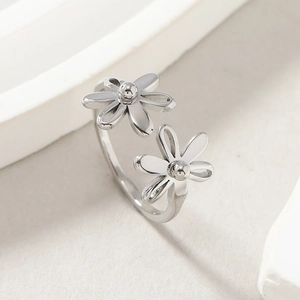 Polished stainless steel open ring with double daisy flowers on white stone background