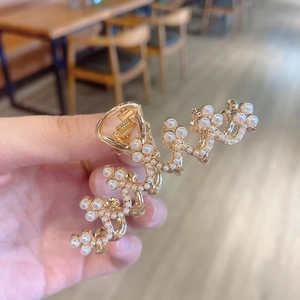 Macro detail of wave-shaped golden metal hair claw clip with faux pearls and rhinestones