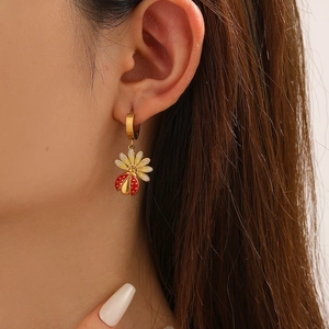Gros plan d'une boucle d'oreille coccinelle et marguerite portée par un mannequin