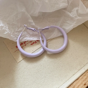 Detail view of purple round hoop earrings on textured paper and linen fabric