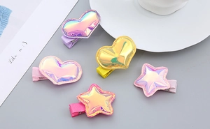 Detail of colorful star and heart hair clips with shiny metallic finish on rib ribbons