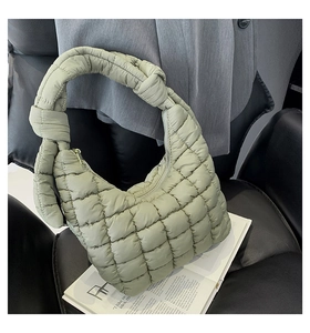 Detail of sage green quilted cloud bag with knot handle on a leather seat