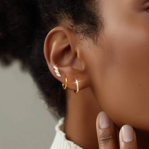 Macro detail of gold S925 silver earring set with stud and hoop on model's ear