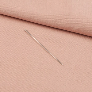 Macro view of silver flat head stainless steel jewelry pin on soft pink fabric