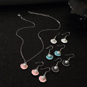 Elegant shell jewelry set with pearl necklace and colorful enamel earrings on dark stones