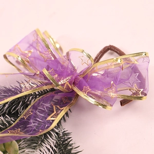 Purple organza Christmas bow with gold stars and pine needle accents on a clean background