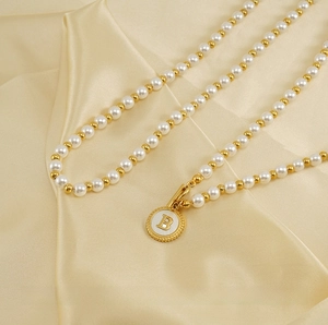 Detail of 18K gold plated OT buckle necklace with shell pearl and letter B pendant