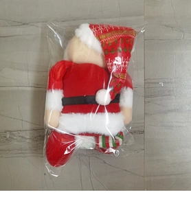 Détail d'une peluche Père Noël avec tenue rouge et bonnet flocon de neige sous emballage