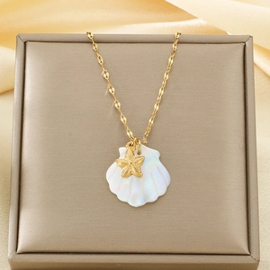 Detail of gold ocean necklace with white shell and starfish pendant in beige jewelry box