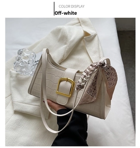 Detail of beige crocodile embossed baguette bag with gold buckle and floral silk scarf