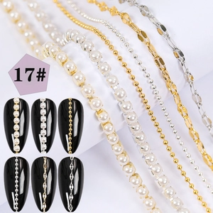 Macro shot of assorted nail art chains with pearls and metal beads on black nails