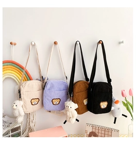 Detail of four colorful corduroy bear crossbody bags with cute plush charms and embroidery