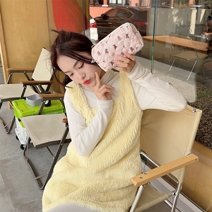 Quilted pink makeup bag with cute bear pattern held by a hand in an outdoor setting