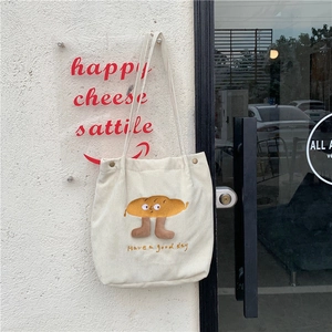 Détail du cabas en velours côtelé avec broderie cartoon et bouton pression en métal