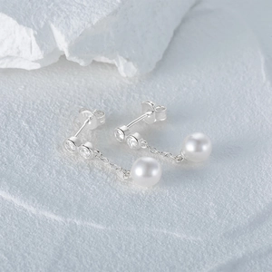 Detail of S925 silver asymmetric earrings featuring small diamonds and white pearls