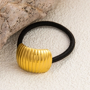 Detail of black woven elastic hair tie featuring a textured gold curved metal ornament