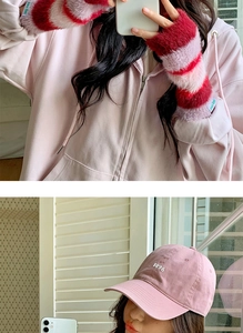 Détail d'un sweat à capuche rose associé à des mitaines en peluche rayées arc-en-ciel
