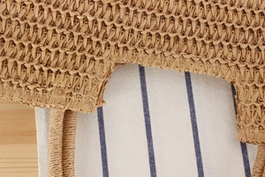 Detailed close-up of woven paper rope texture and handle on a brown straw shoulder bag