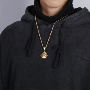 Gros plan d'un pendentif soleil doré avec chaîne torsadée sur un modèle de style rétro
