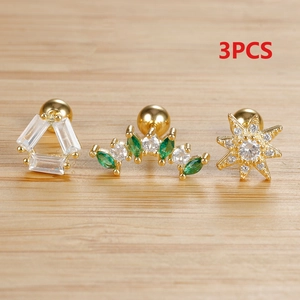 Three-piece gold star stud earrings set with green and white zircon on wood texture