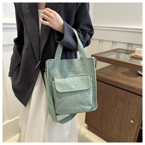 Detail of mint green corduroy tote bag featuring adjustable strap and front flap pocket