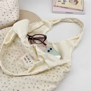 Detail of corduroy tote bag lining with brand label and everyday items storage space