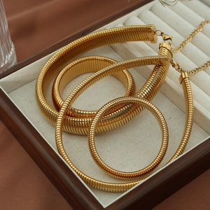 Set of four layered golden flat snake chain necklaces on a beige velvet jewelry box