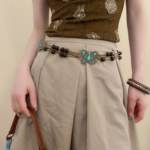 Detail of bohemian waist chain featuring wood beads and blue gemstone butterfly buckle