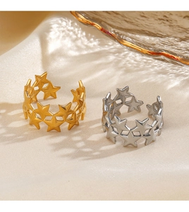 Detail of adjustable star cut-out rings in gold and silver on soft beige silk fabric