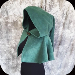 Detail view of green hooded medieval capelet with two wooden buttons on mannequin