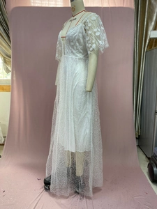 Detail of white bridal gown featuring intricate daisy lace embroidery and puff sleeves