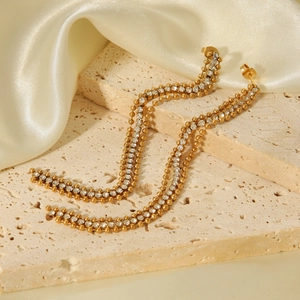 Gros plan détaillé de longues boucles d'oreilles dorées avec cristaux sur pierre