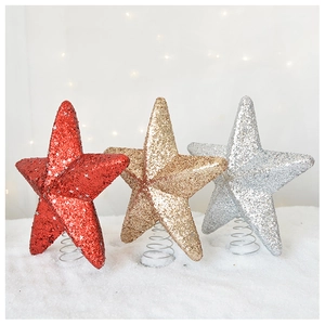 Detail of red, gold and silver glitter star tree toppers on snow background