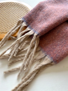 Close-up of pink-brown thick knit scarf with speckled texture and long beige tassels